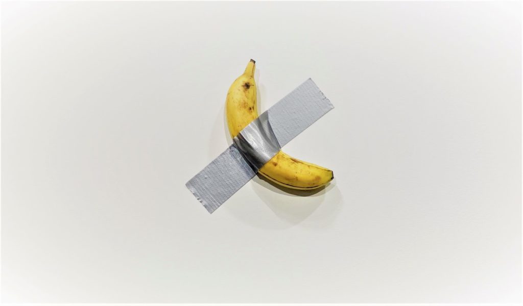 fresh banana taped to a wall with a piece of duct tape