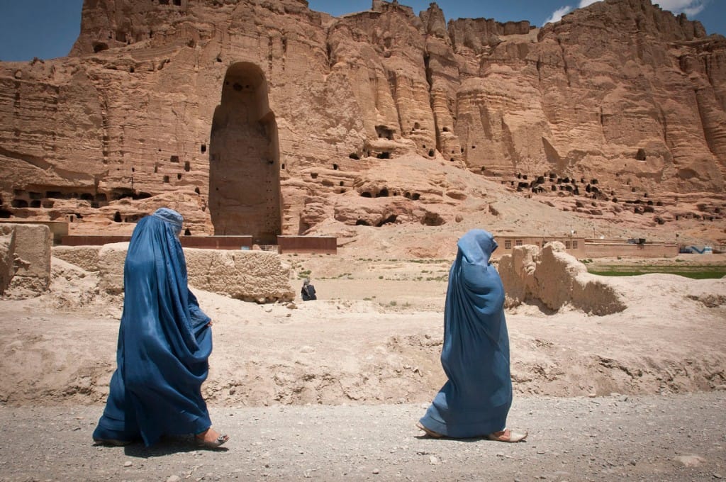 Two women walk past the huge cavity where one of the ancient Buddhas of Bamiyan, known to locals as the Father Buddha